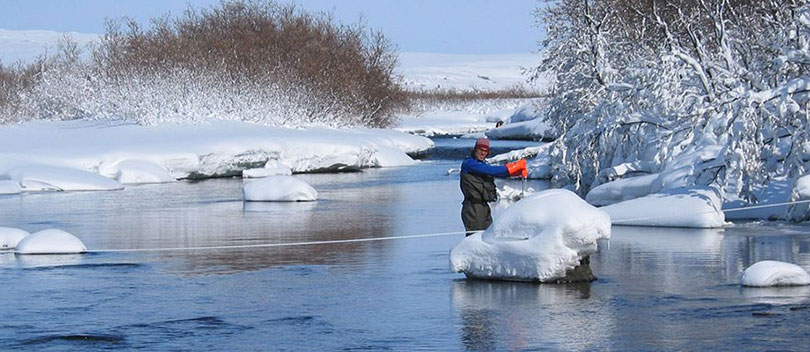 A hydrographer working on a river in the wintertime.