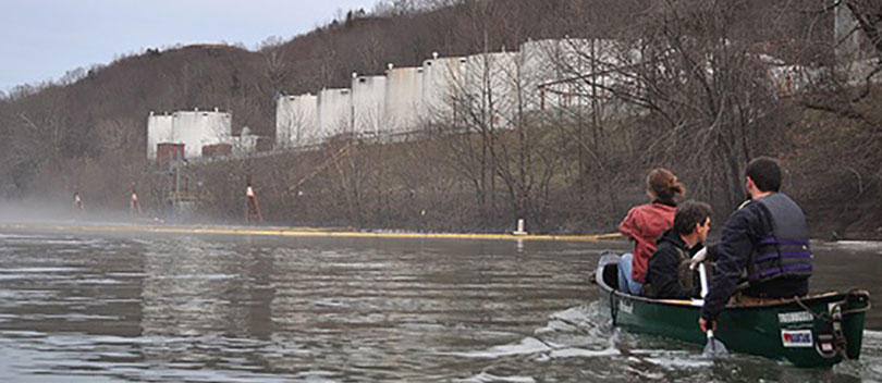 Three people in a row boat on a river in West Virginia.