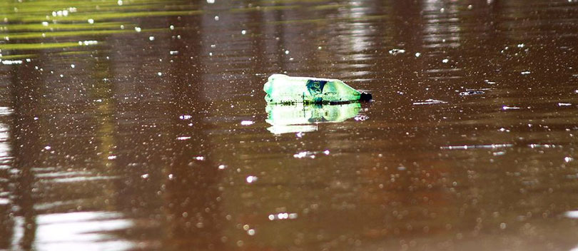 Plastic bottle floating on a brown river.