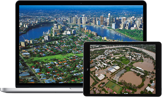 Laptop Displaying Dry Aerial City View, Tablet Displaying Flooded Aerial View.