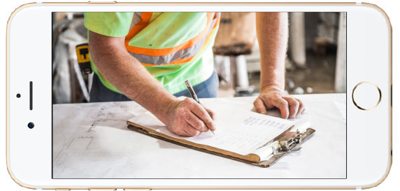 A construction working completing a form on a clipboard.